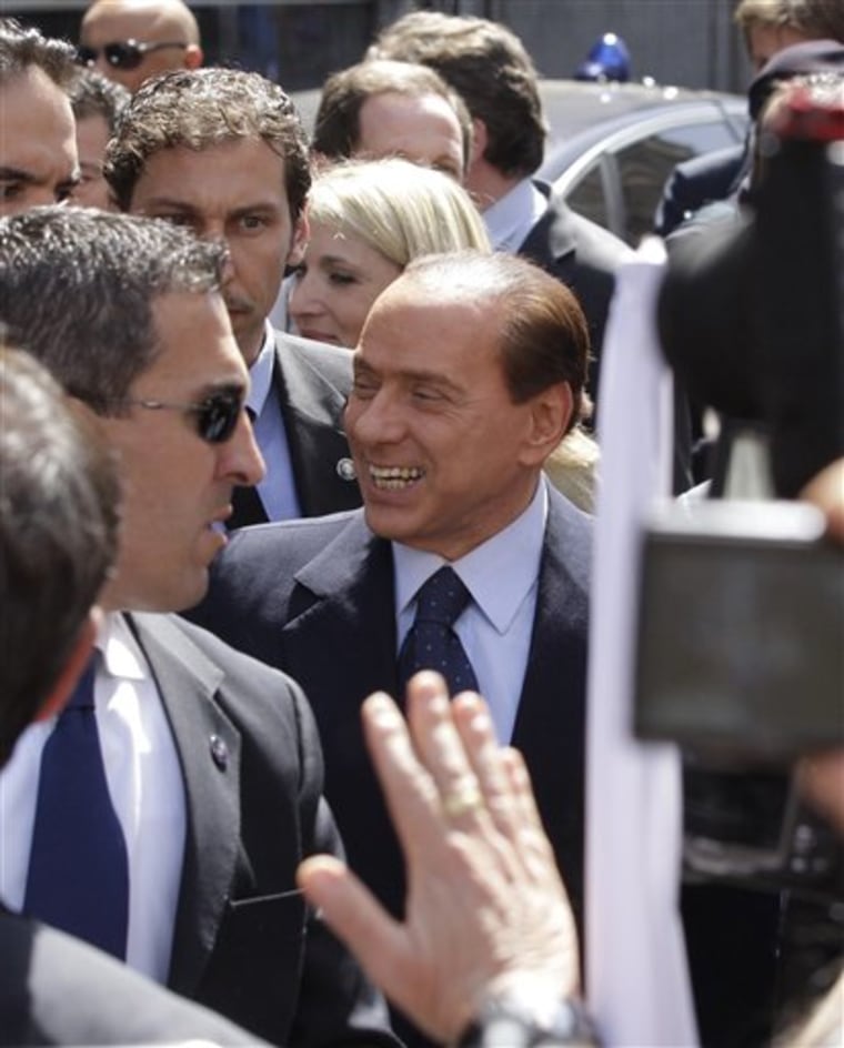 Italian Premier Silvio Berlusconi, center, flanked by his bodyguards, smiles as he speaks to his supporters outside Milan's courthouse where he attended his trial on tax fraud charge, on Monday, April 11. Berlusconi says attending a hearing of his tax fraud trial in Milan was a waste of time and resources.